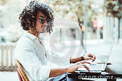 Asian young businessman with laptop in a cafe outdoors Stock Photo