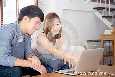 Asian young couple using laptop computer think and searching internet together, man and woman casual smiling work at home Stock Photo