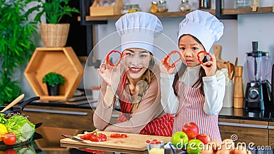 Asian young female chef housewife mother and little cute girl daughter wears white tall cook hat and apron smiling holding posing Stock Photo