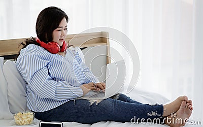 Asian young happy funny fat chubby oversized woman wears big red headphones around head listening to music and sit enjoy alone Stock Photo