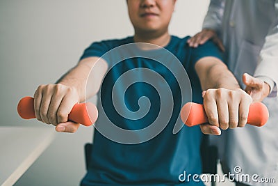 Asian young male physiotherapist helping patient with lifting dumbbells exercises in office Stock Photo