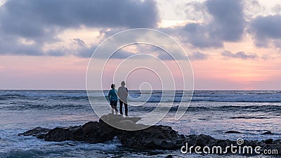 Asian young man and woman standing on a rock watching sunset. Editorial Stock Photo