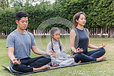 Mother, father practicing doing yoga exercises with child daughter outdoors in meditate pose together Editorial Stock Photo