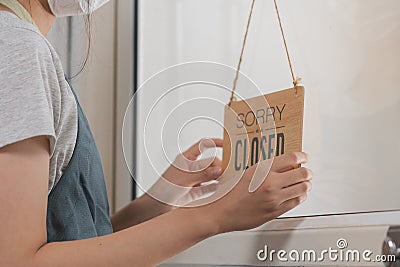 Asian young owner retail,coffee shop woman turning sign board to closed with wearing face mask,protection to pandemic of Stock Photo