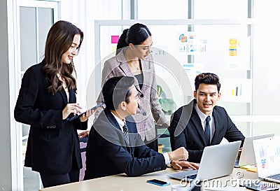 Asian young professional successful businesswoman employee colleagues in formal suit sitting standing in meeting room, typing Stock Photo