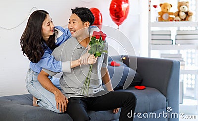 Asian young romantic lover couple female girlfriend holding red roses bouquet hugging cuddling surprising male boyfriend Stock Photo