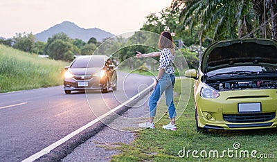 Asian young woman with broken car showing hitchhiking on the roadside. Problems with cars on the road. Stock Photo