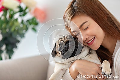 Asian young woman playing with her pet and smile with pug dog Stock Photo
