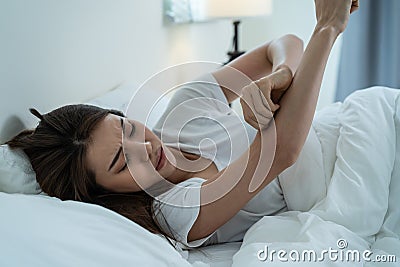 Asian young woman scratch hand feel suffer from allergy while sleeping. Beautiful attractive girl lying on bed in bedroom Stock Photo