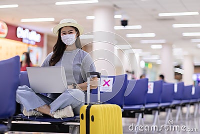 Asian young woman wearing face maks using laptop computer at airport Stock Photo