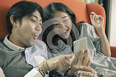 asian younger man and woman watching on smart phone with surprising and happiness face,internet and social media concept Stock Photo