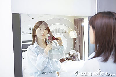 Asians girl is brushing her hair in front mirror at morning Stock Photo