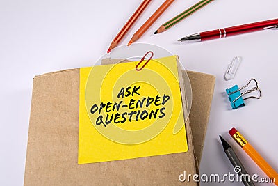 ASK OPEN-ENDED QUESTIONS. Stack of books on a white office desk Stock Photo