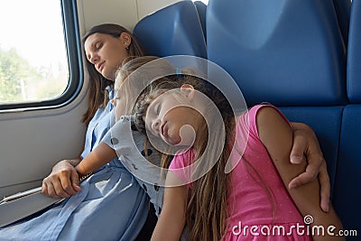 Asleep mom and daughters fell asleep in an electric train car Stock Photo