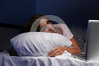 Asleep young internet addict woman in the bed with laptop. Stock Photo