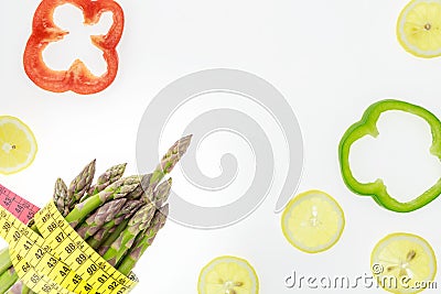Asparagus spears with measuring tape, lemon slices and pepper rings, on white background Stock Photo