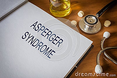 Asperger syndrome written on book with tablets Stock Photo