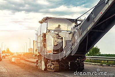 Asphalt milling and grinding machine at road repair and construction site. Highway renewal with heavy machinery Editorial Stock Photo