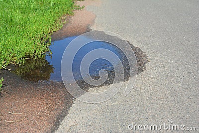 Asphalt on puddles. Pot hole or pothole image of a broken cracked asphalt pavement. Stock Photo