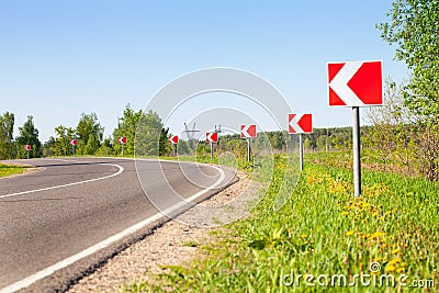 Asphalt road with bright traffic signs in situ of the sharp left turn Stock Photo