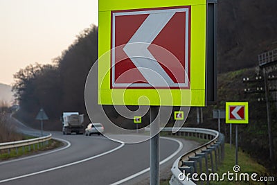 Asphalt road with bright traffic signs in situ of the sharp left turn Stock Photo