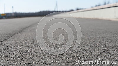 Asphalt road with concrete fence going into the distance with a blurred background Stock Photo