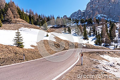 Asphalt road in the Dolomites in the spring. Mountains and forests against a blue sky Stock Photo