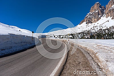 Asphalt road in the Dolomites in the spring. Mountains and forests against a blue sky Stock Photo