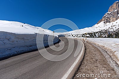 Asphalt road in the Dolomites in the spring. Mountains and forests against a blue sky Stock Photo