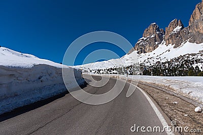 Asphalt road in the Dolomites in the spring. Mountains and forests against a blue sky Stock Photo