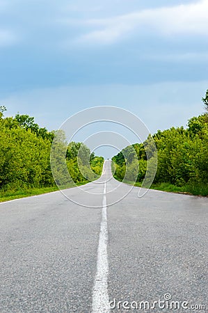 Asphalt road, goes into the distance. Green trees are on both sides. Stock Photo