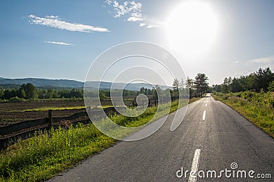 Asphalt road with plowed field and mountain Papuk in the background, Croatia Stock Photo