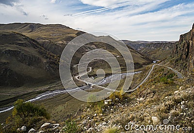 The asphalt serpentine track winds and meanders along the mountain slope and valley Stock Photo