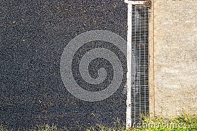 Asphalt used for surfacing roads, local street cover with asphalt with drain, black rough textured background Stock Photo