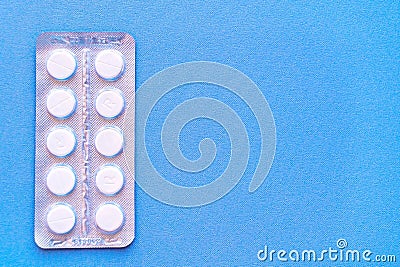 Aspirin in a blister on top. Vitamin C pills in a pack. White tablets in a blister on a blue background close-up with soft focus. Stock Photo