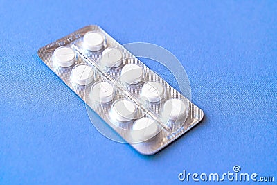 Aspirin in a blister on top. Vitamin C pills in a pack. White tablets in a blister on a blue background close-up with soft focus. Stock Photo