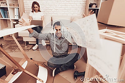 Man Sits on Foor Throwing Furniture Instructions. Stock Photo