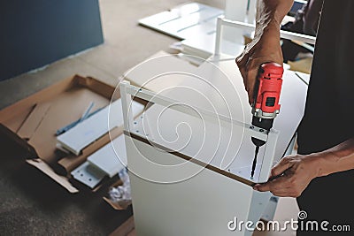 Assembling Furniture at Home. Moving for a New House or DIY Concept. Craftsman using Cordless Screwdriver Stock Photo