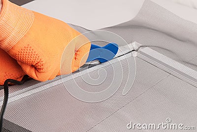 Assembling mosquito net for window, installing seal in an aluminum profile Stock Photo