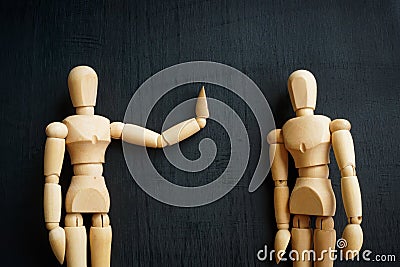 Assertiveness and confidence concept. Two wooden figurines on the dark surface. Stock Photo