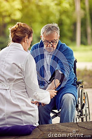 Assessment of blood pressure elderly man in wheelchair Stock Photo