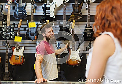 Assistant showing customer guitar at music store Stock Photo