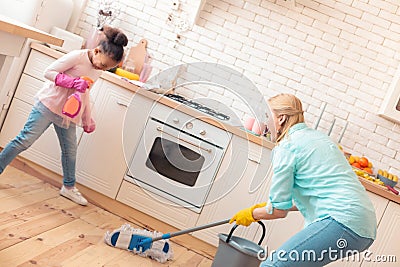 Cute helpful girl assisting her mother with cleaning the kitchen Stock Photo