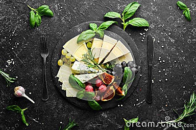 Assorted cheeses on a plate. Parmesan cheese, blue cheese and brie on a plate with grapes and figs. Antipasto. Top view Stock Photo