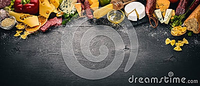 Assorted cheeses, sausages, wines, traditional spices and fresh vegetables on a wooden background. Stock Photo