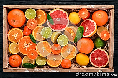 Assorted citrus fruit in a wooden box. Orange, tangerine, grapefruit, lemon. On a wooden background. Stock Photo