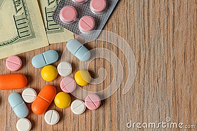 Assorted colored pills and money on the table. The concept of buying pills. The concept of increasing the price of tablets Stock Photo