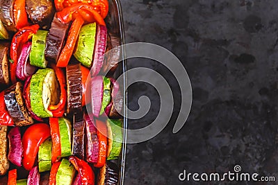 Assorted different bright and juicy baked vegetables, zucchini, eggplant, zucchini, tomato, pepper, onion on a dark retro Stock Photo