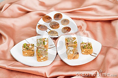 Assorted dry fruit Indian sweets with dry figs in three plates on a satin fabric Stock Photo