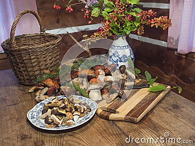 Assorted edible mushroom Boletus close up on wooden rustic table with wicker basket, autumnal flower bouquet, cutting Stock Photo